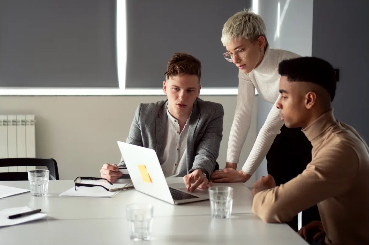 Colleagues collaborating around a laptop in a modern office