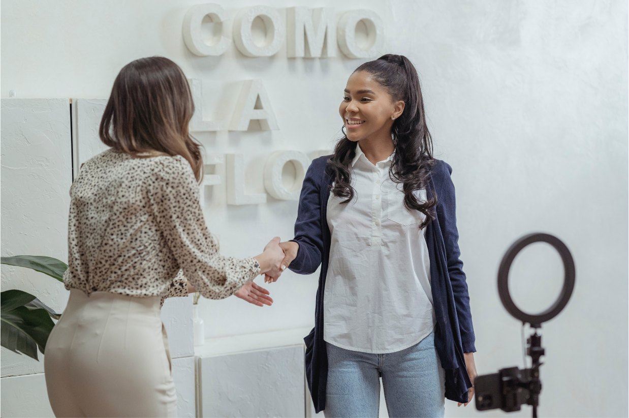 Recruiter greeting a candidate with a handshake in a bright studio office